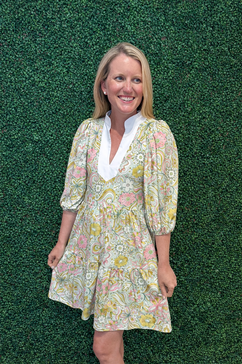 girl wearing colorful smith and quinn dress in front of green wall