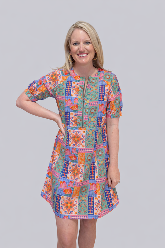 Woman wearing a colorful patchwork dress on a gray background